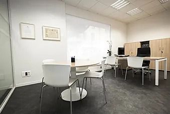 Sala de reuniones de oficina moderna con sillas blancas, una mesa, armarios y una pizarra blanca en la pared.