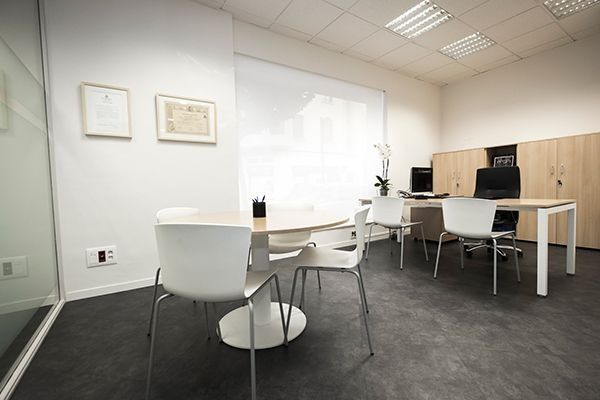 Sala de reuniones moderna con sillas blancas, mesa de madera, pizarra blanca y armarios.
