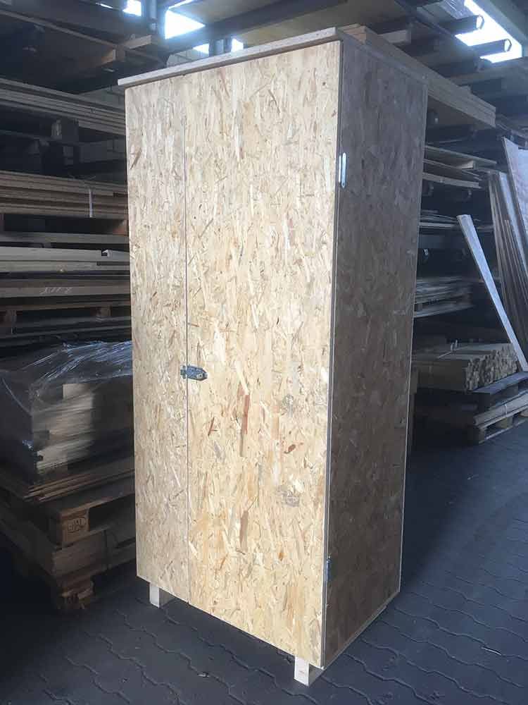 In einem Lagerhaus steht neben einem Holzstapel ein Holzschrank.