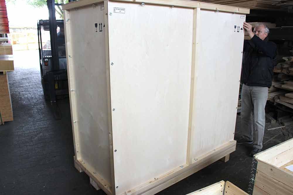 Ein Mann steht neben einer großen Holzkiste.