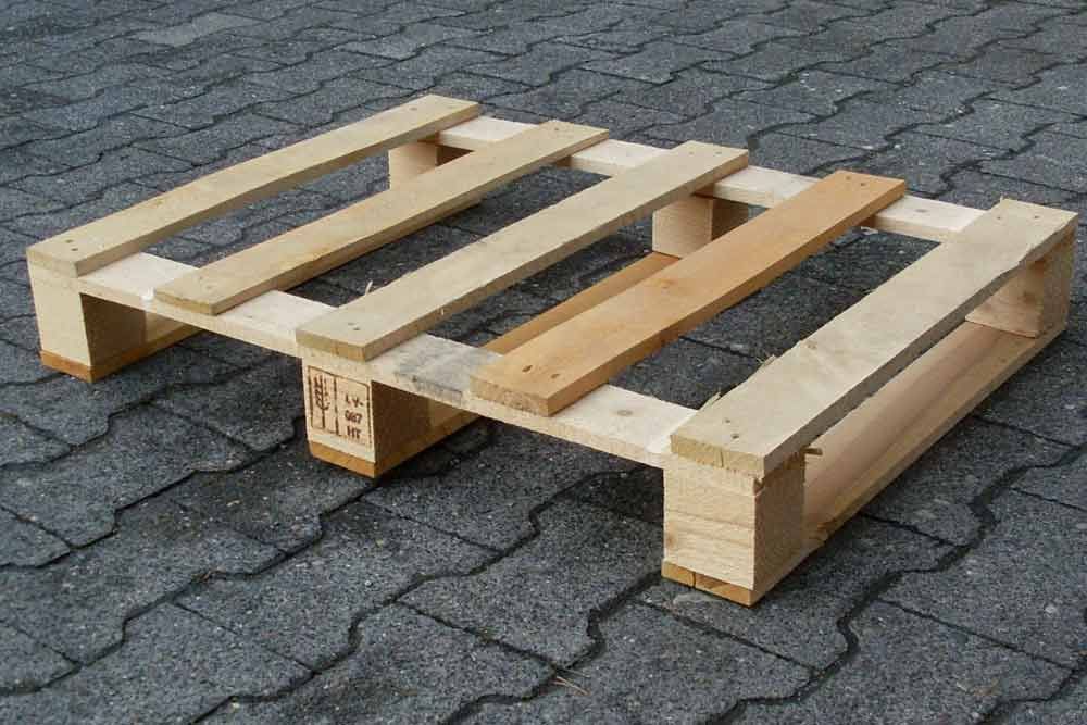 Eine Holzpalette steht auf einem Ziegelpflaster.