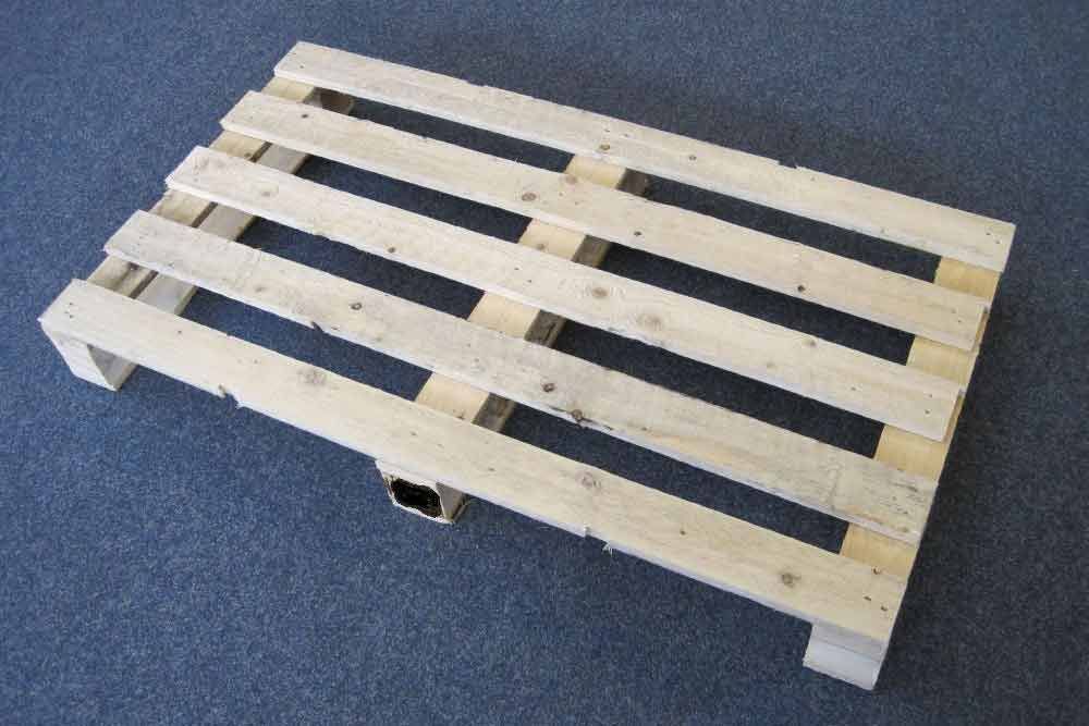 Auf einem Teppichboden steht eine Holzpalette.