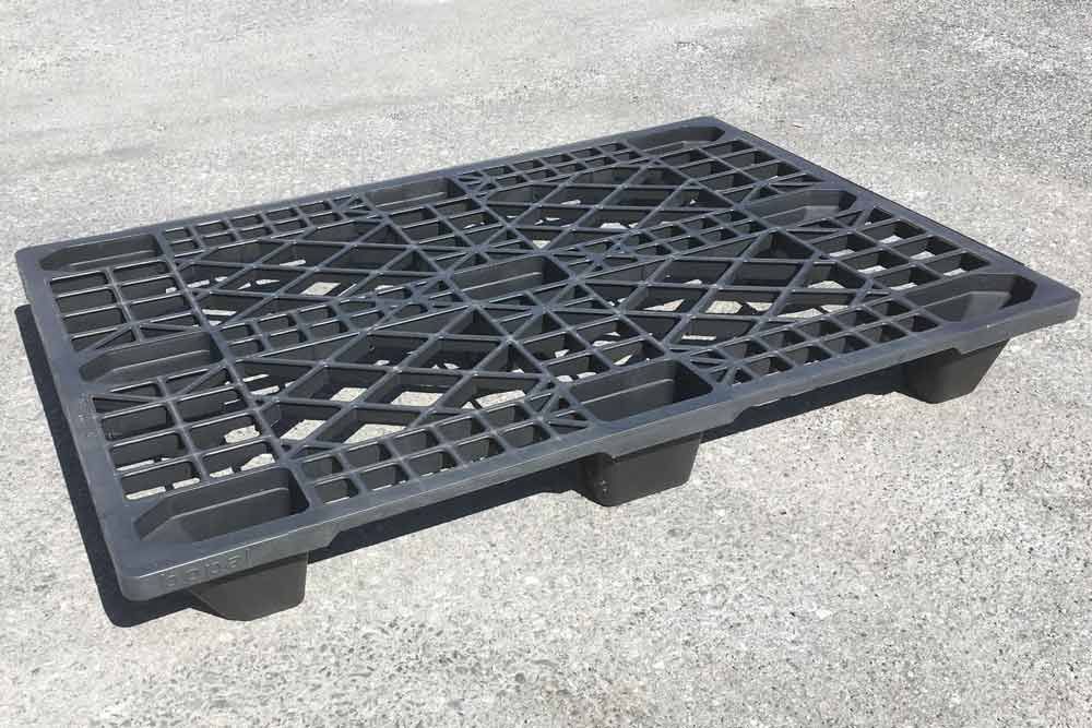 Eine schwarze Kunststoffpalette steht auf einer Betonoberfläche.