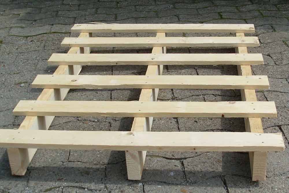 Auf einem gepflasterten Gehweg steht eine Holzpalette.
