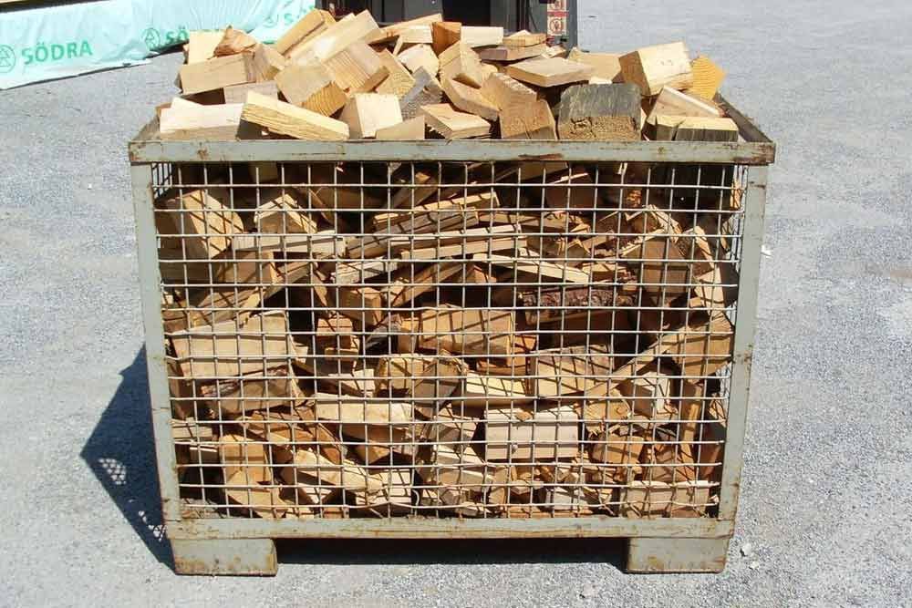 Eine mit Holz gefüllte Metallkiste steht auf dem Boden