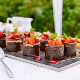 Una bandeja de postres de chocolate con fresas encima.