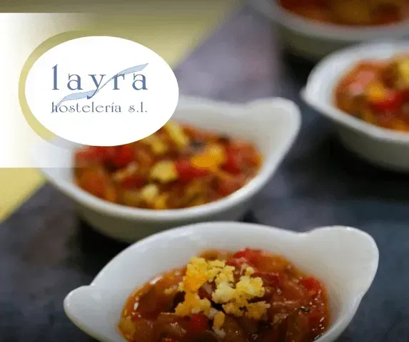 Varios cuencos de comida con el logotipo de Layra Hostelería SL al fondo.