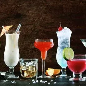 Una variedad de cócteles están sentados en una mesa de madera.