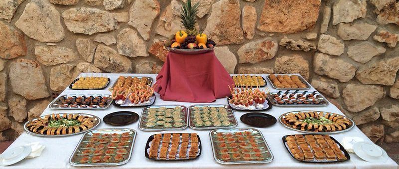 Una mesa con una variedad de alimentos frente a una pared de piedra.