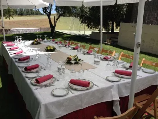 Una mesa larga con platos y sombrillas encima.