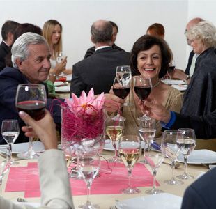 Un grupo de personas está sentado en una mesa brindando con copas de vino.