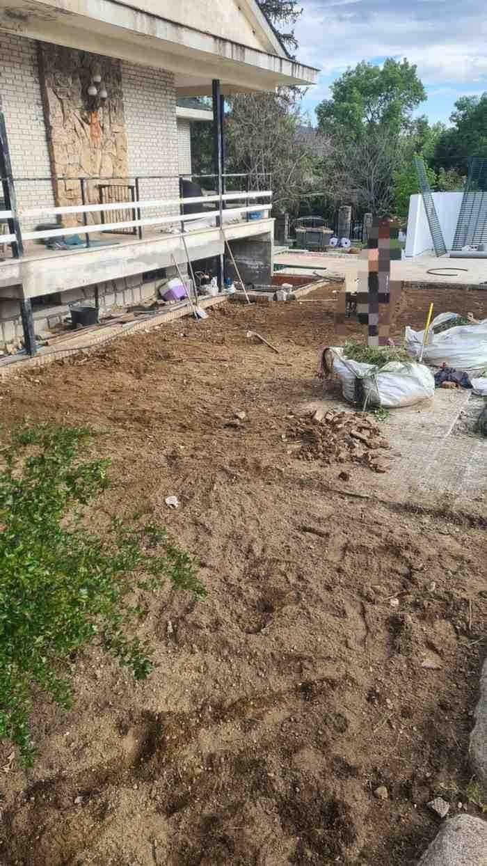 Un proyecto de construcción exterior sin terminar que consiste en un patio de tierra junto a una casa.