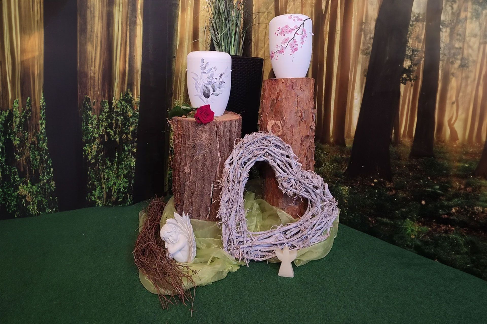 Ein herzförmiger Kranz liegt auf einem Tisch neben einem Baumstumpf.