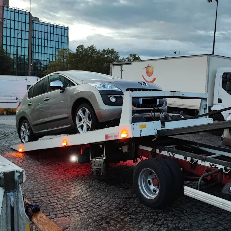 Une voiture beige est remorquée sur un camion plateau.