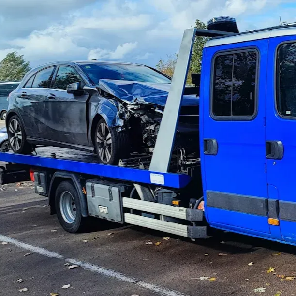 Voiture grise endommagée sur une dépanneuse bleue, partie avant détruite.