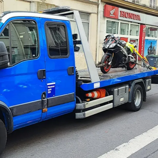 Une dépanneuse bleue transporte une moto sport dans une rue de la ville.