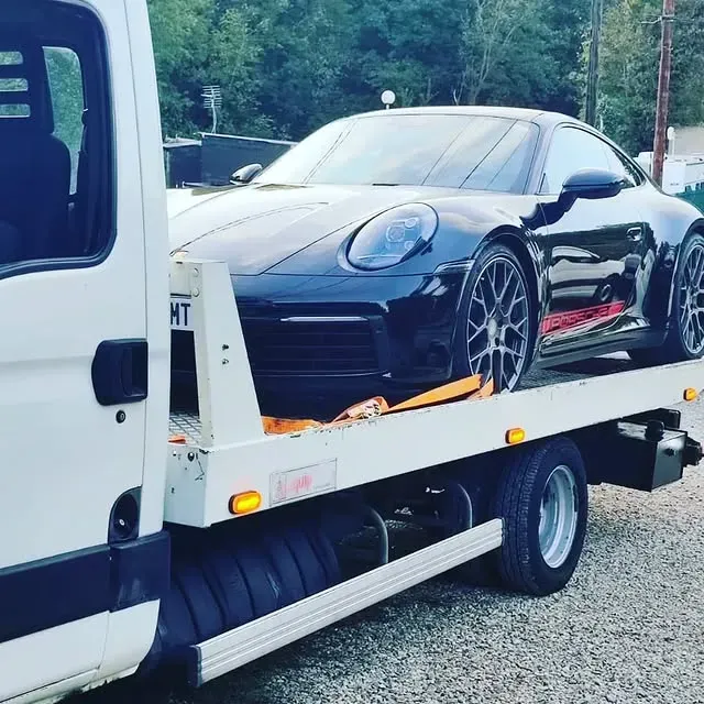 Voiture de sport Porsche noire sur une dépanneuse blanche.