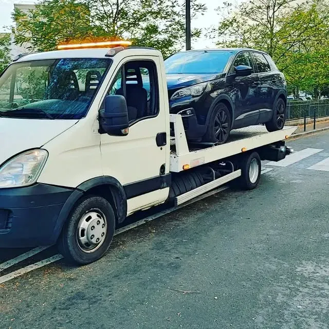 Dépanneuse transportant une voiture noire dans une rue de la ville.