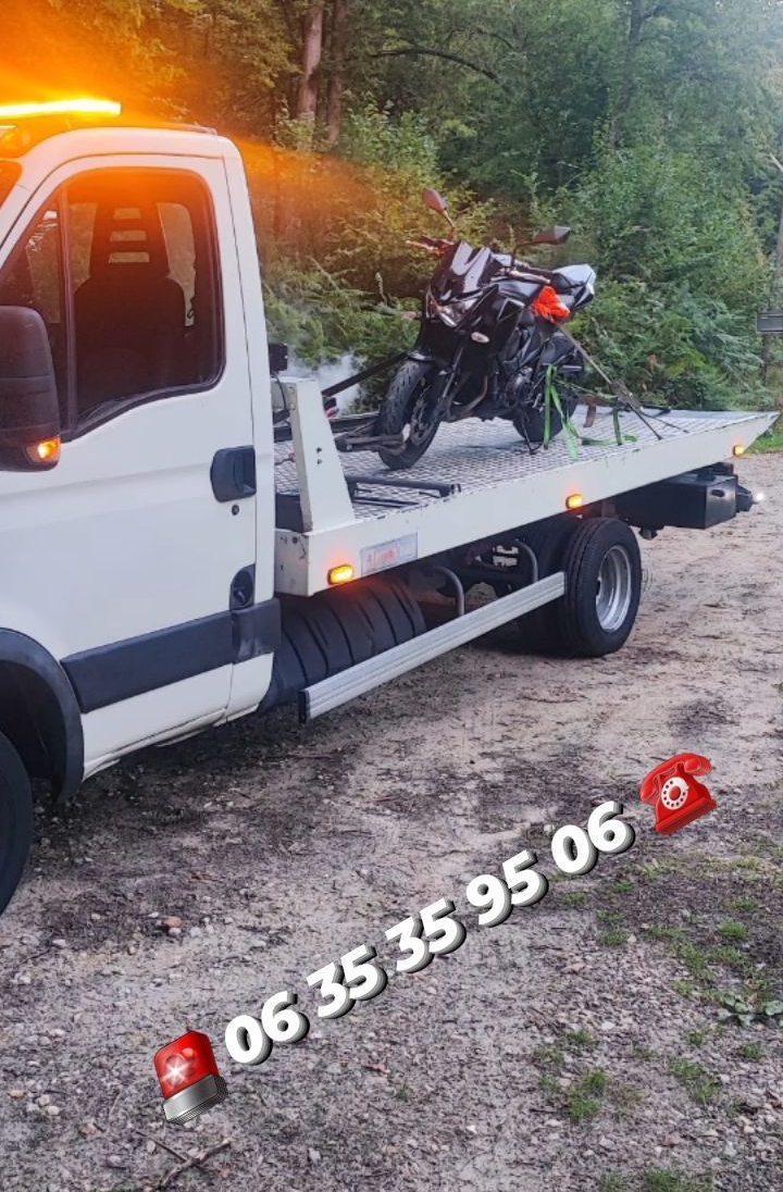 Une dépanneuse blanche avec une moto sur son plateau.