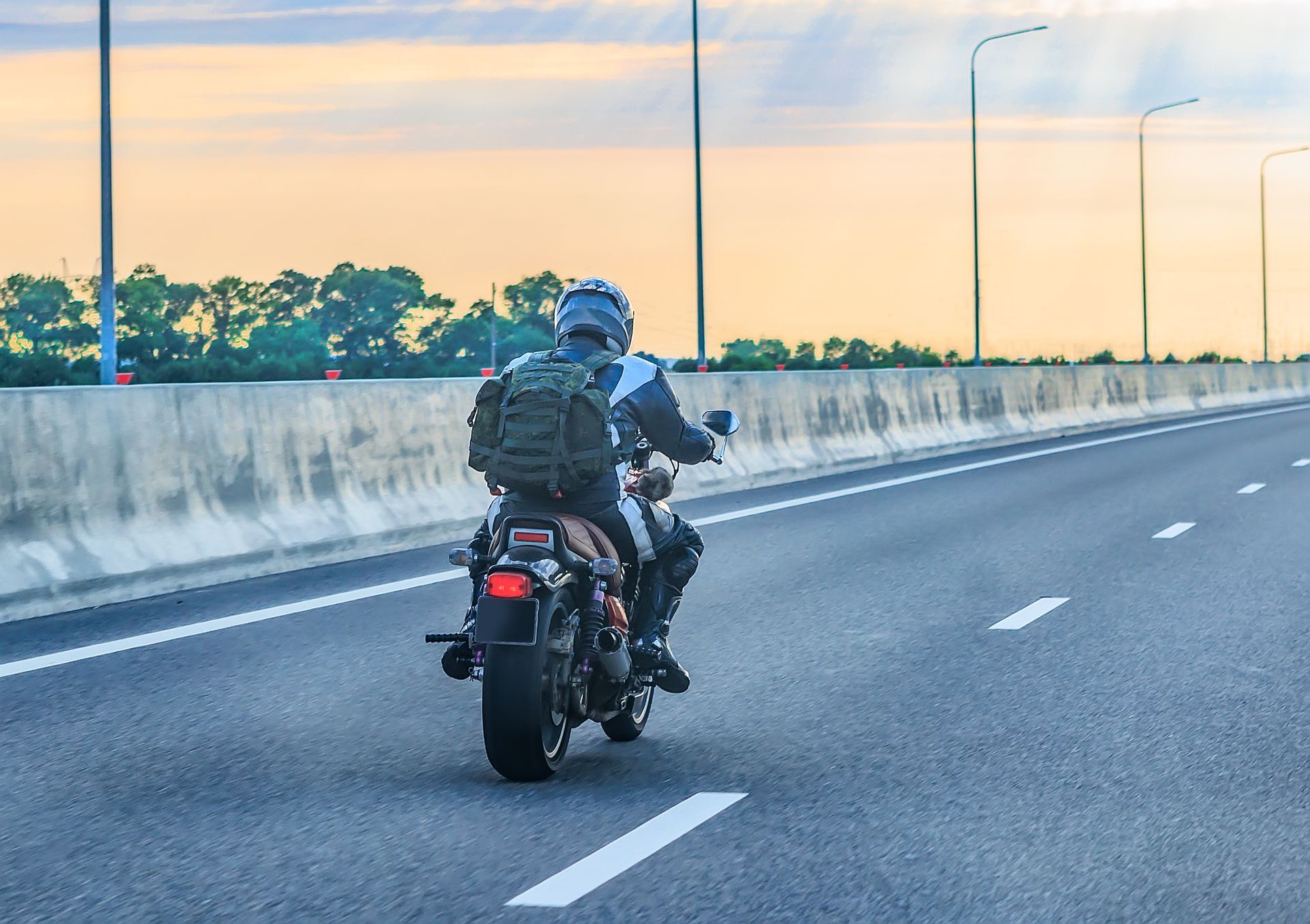 Un motocycliste circulant sur une autoroute avec un sac à dos.