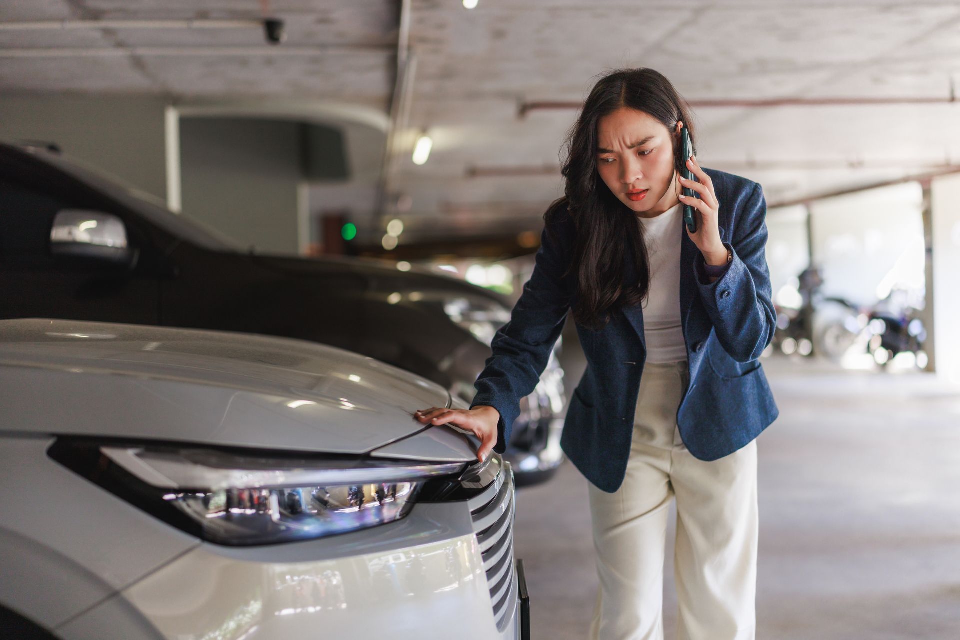 Jeune femme en train de vérifier le parchoc avant de sa voiture
