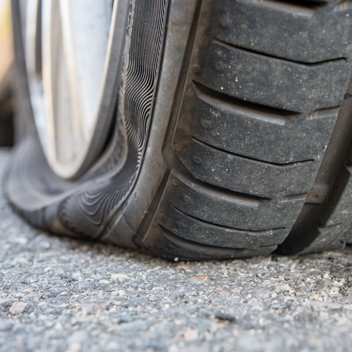 Pneu de voiture dégonflé sur le trottoir.