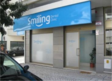 Um carro está estacionado em frente a uma clínica odontológica sorridente