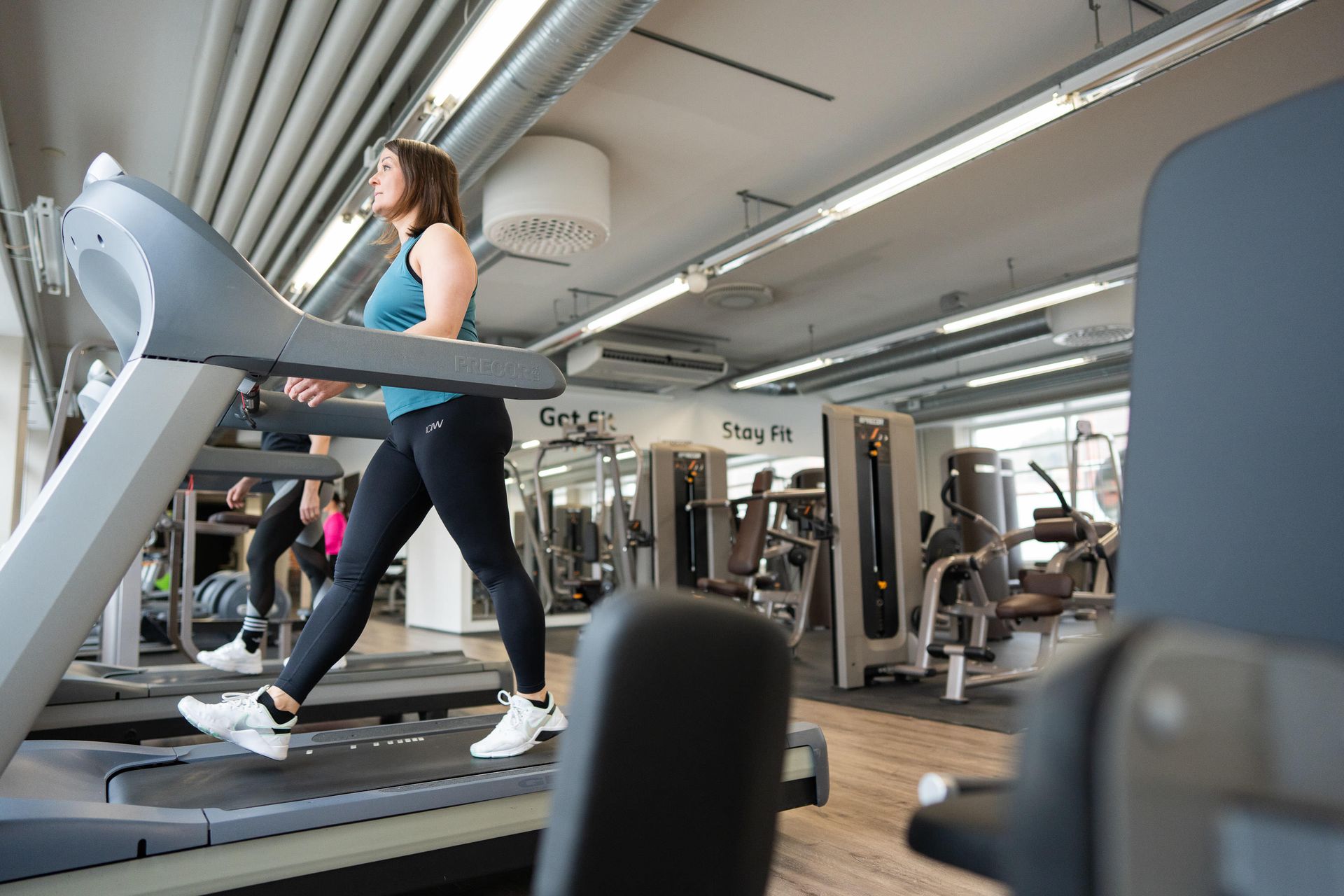 Nainen juoksee juoksumatolla kuntosalilla