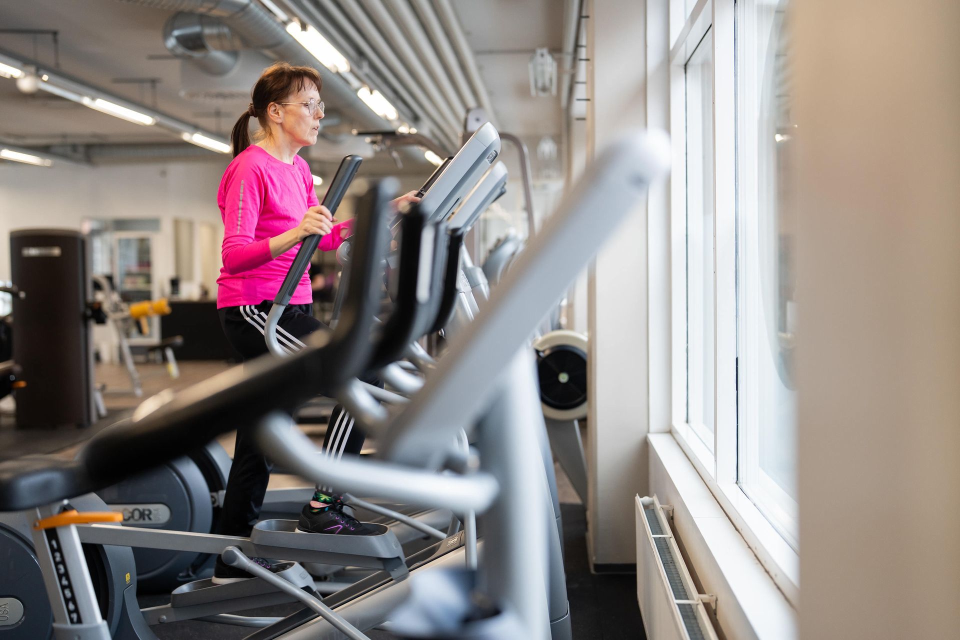 Nainen juoksee juoksumatolla kuntosalilla