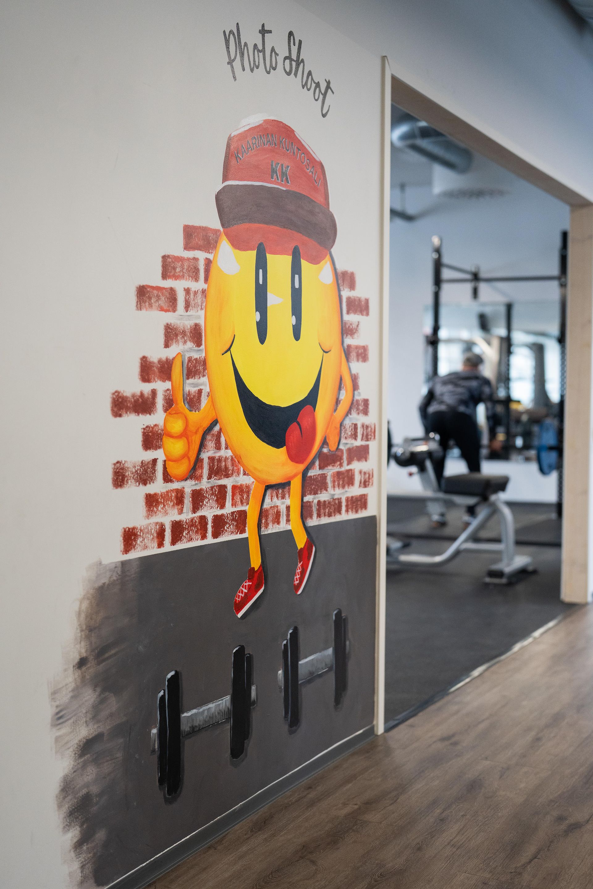 Hymyilevän kasvot esittävä maalaus kuntosalin seinällä