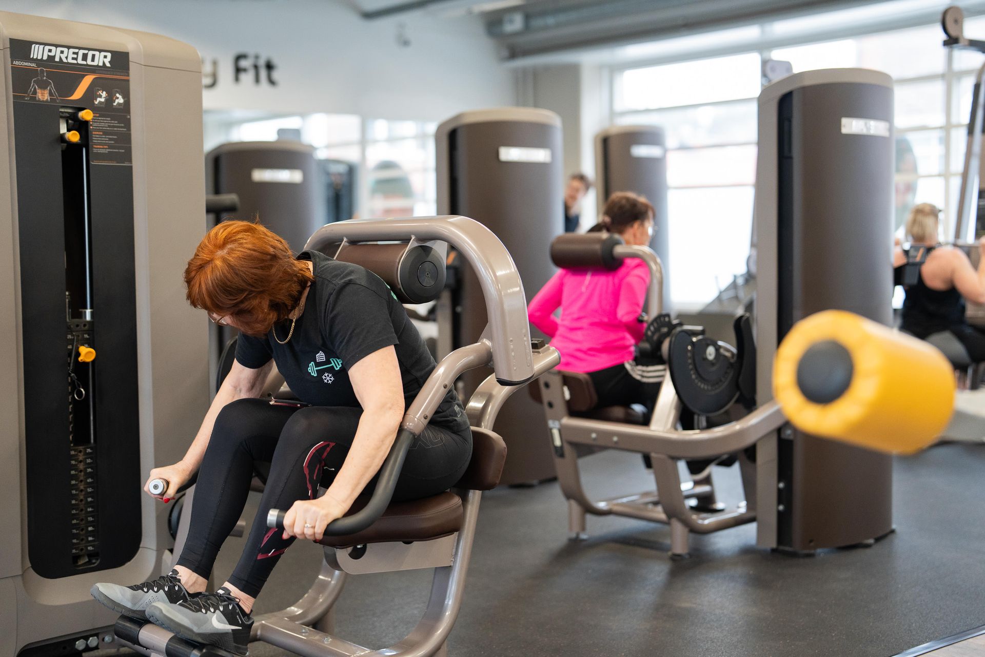 Nainen käyttää kuntosalilla laitetta, jossa lukee