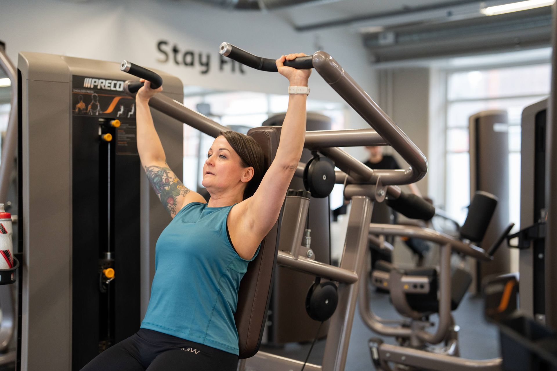 Nainen käyttää kuntosalilla laitetta, jossa lukee