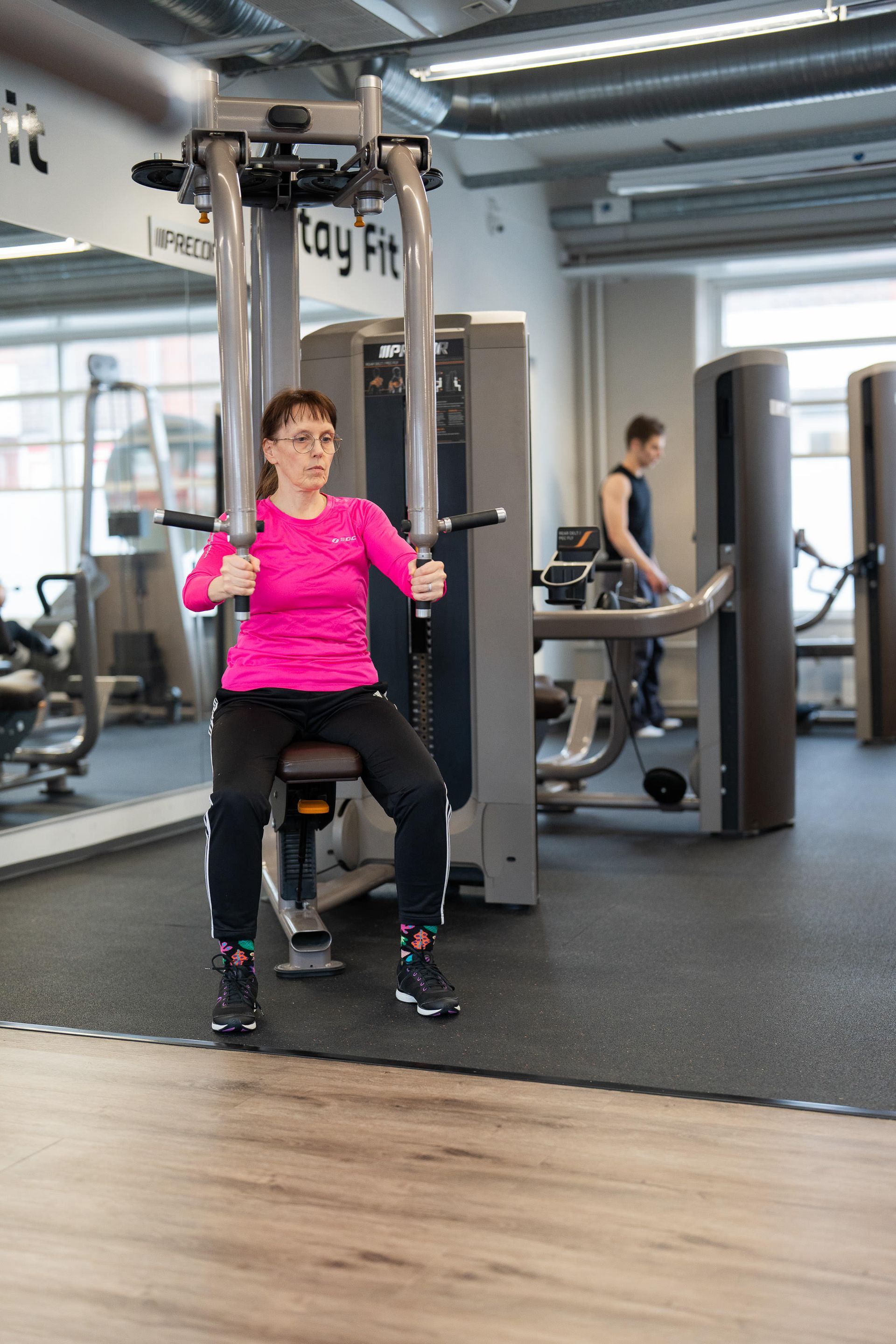 Nainen käyttää kuntosalilla laitetta, jossa lukee 