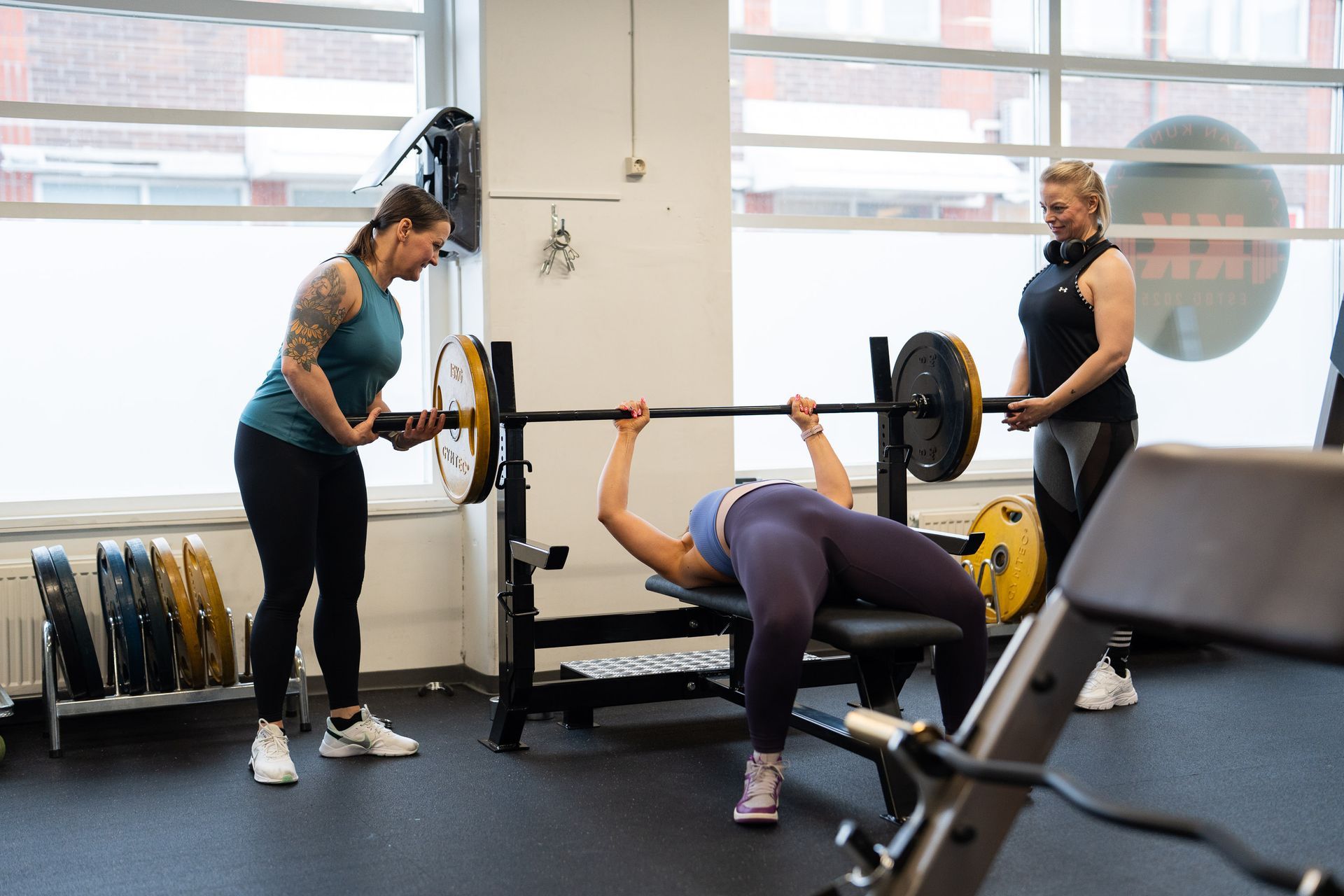 Nainen nostaa tankoa kuntosalilla