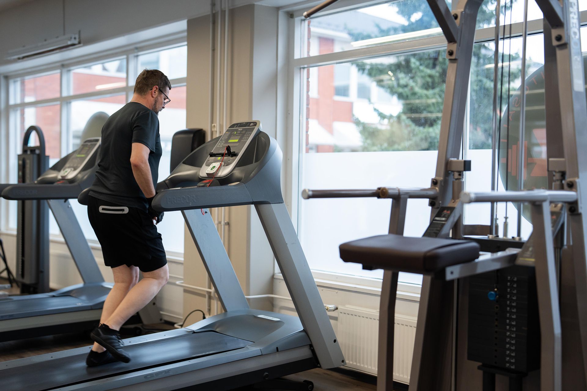 Mies juoksee juoksumatolla kuntosalilla