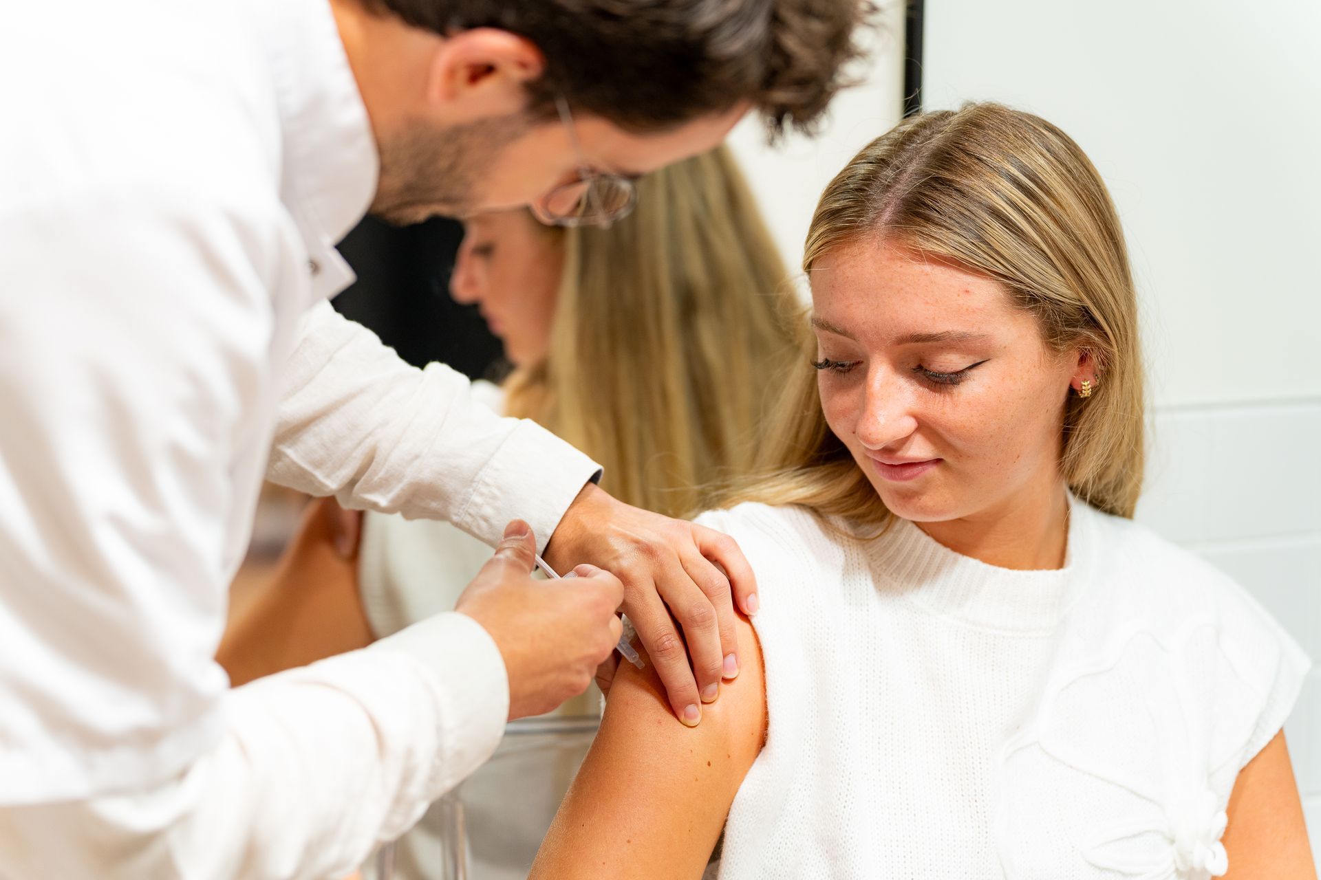 Une pharmacienne en train de vacciner une personne.