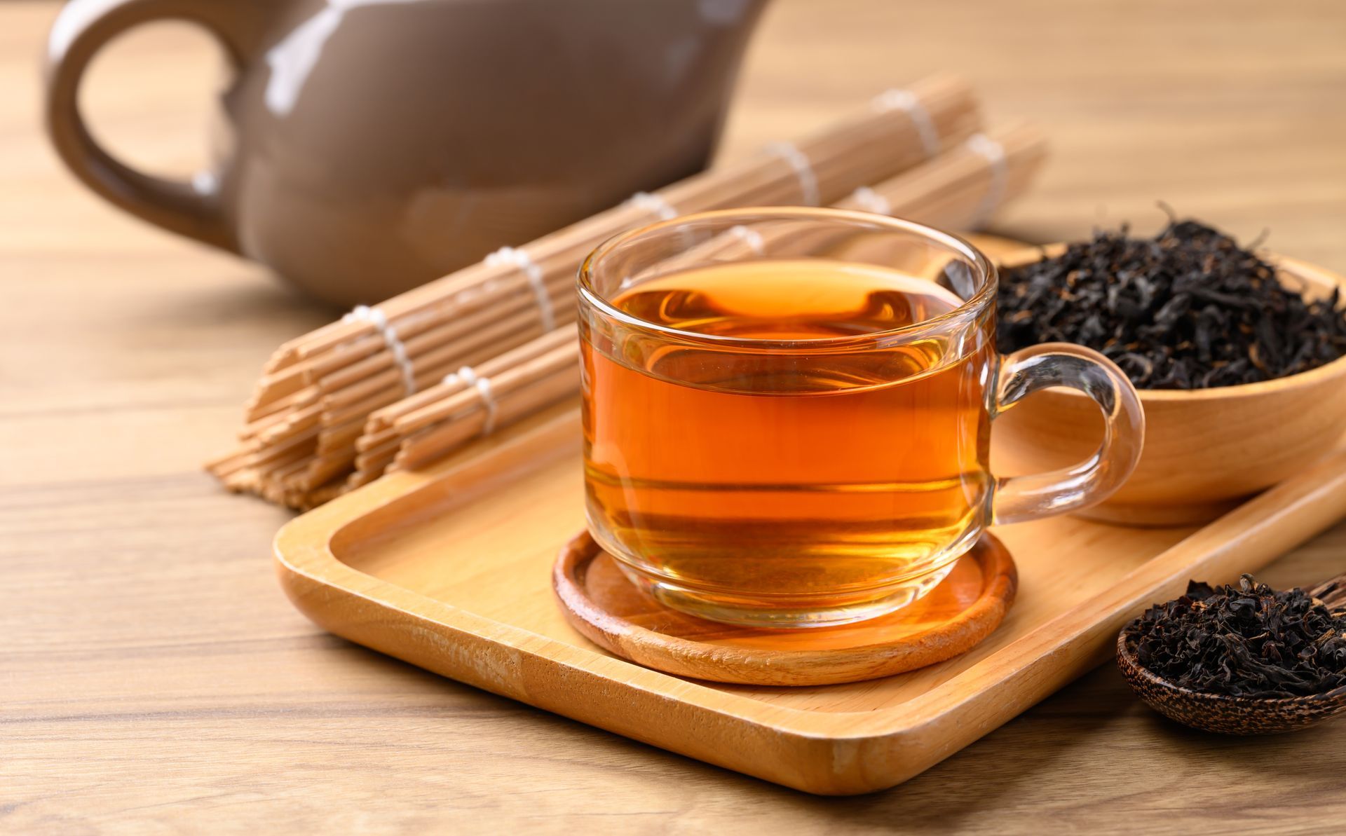 Une tasse de thé à proximité d'un récipient rempli d'herbe noire.