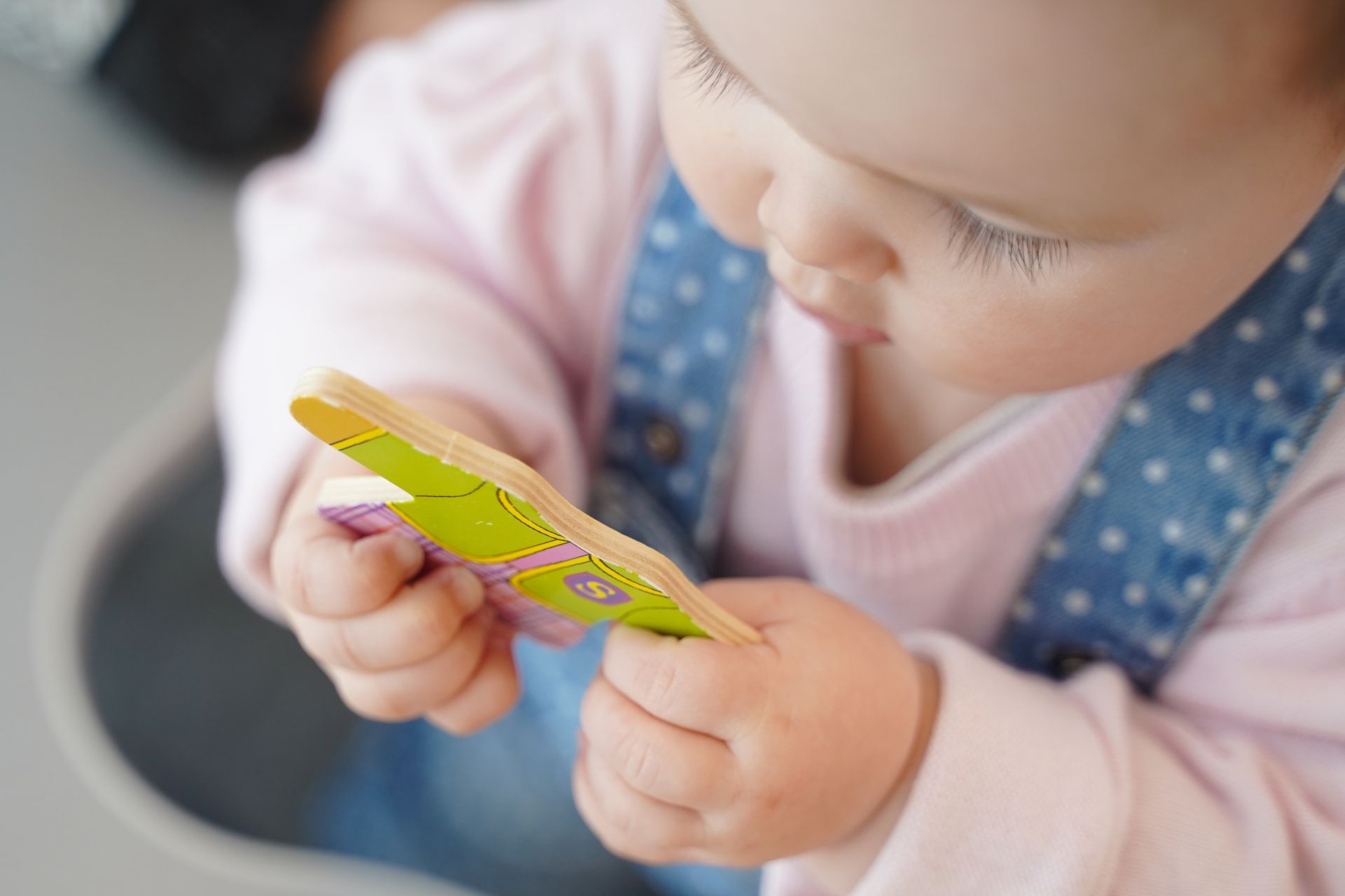 Un bébé tenant un jouet en bois dans les mains.