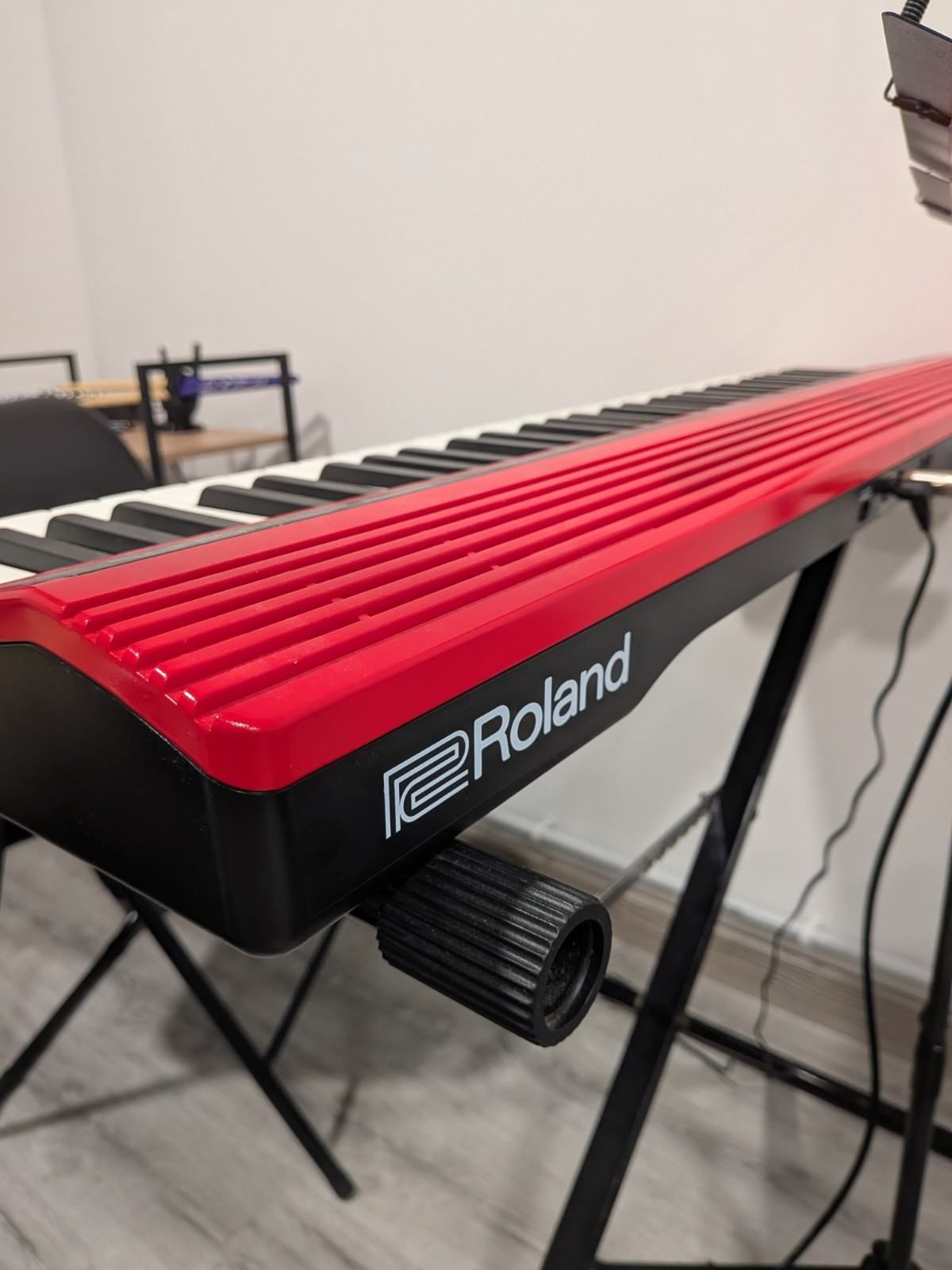 Teclado Roland con teclas de color rojo brillante sobre un soporte en una habitación