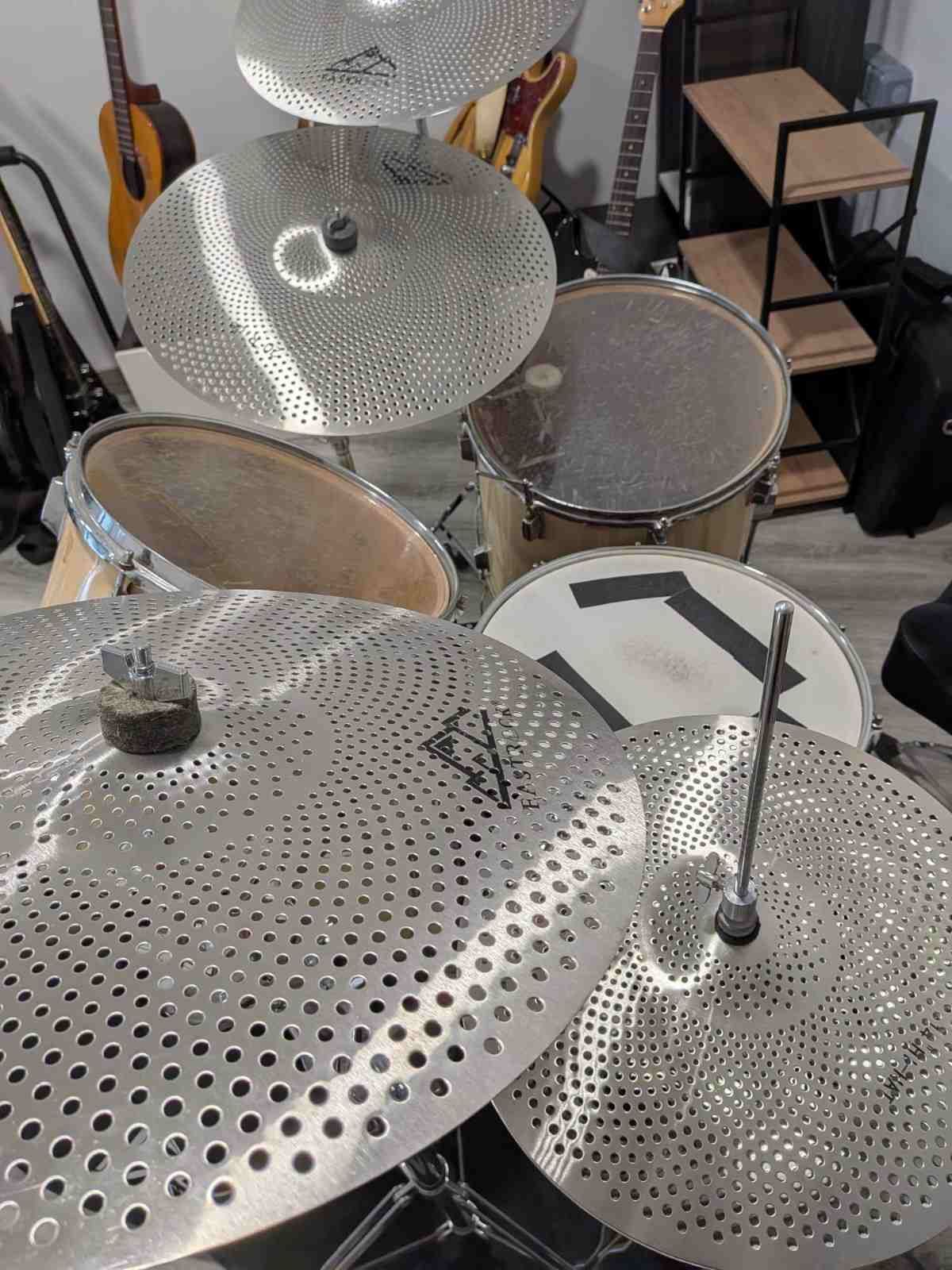 Primer plano de una batería con platillos perforados y toms relucientes en una sala de música