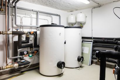 Deux réservoirs d'eau chaude dans un local technique avec des tuyaux et des récipients sous pression fixés aux murs.