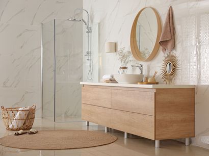 Une salle de bains moderne avec un meuble-lavabo en bois, des murs à motifs marbrés, un miroir rond et une douche à l'italienne avec un tapis de paille.