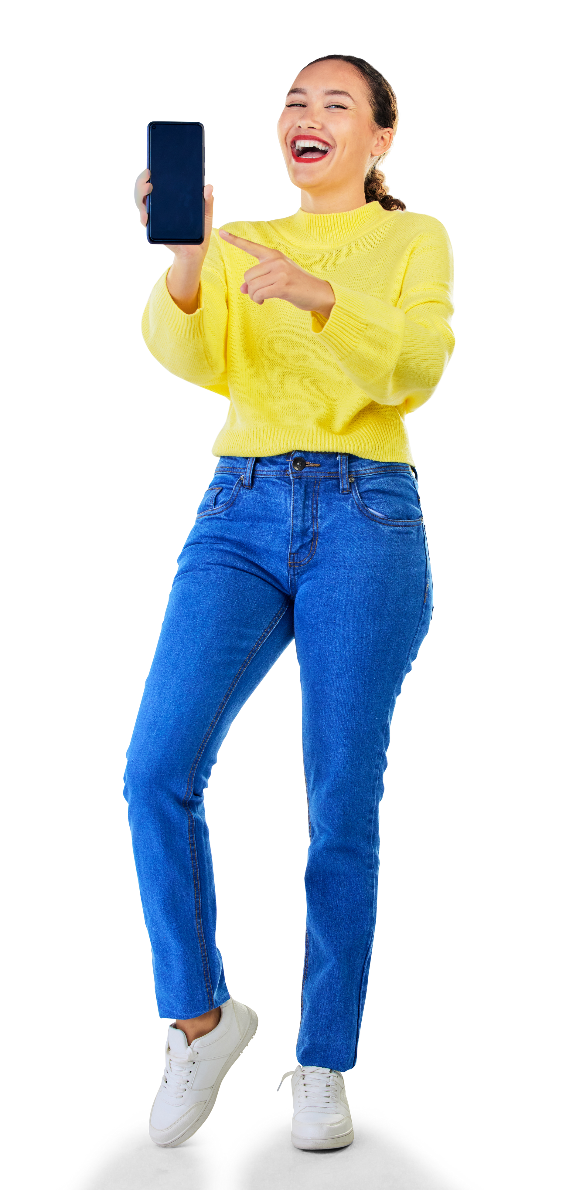 Une personne souriante, vêtue d'un pull et d'un jean, brandit et désigne un écran de smartphone.