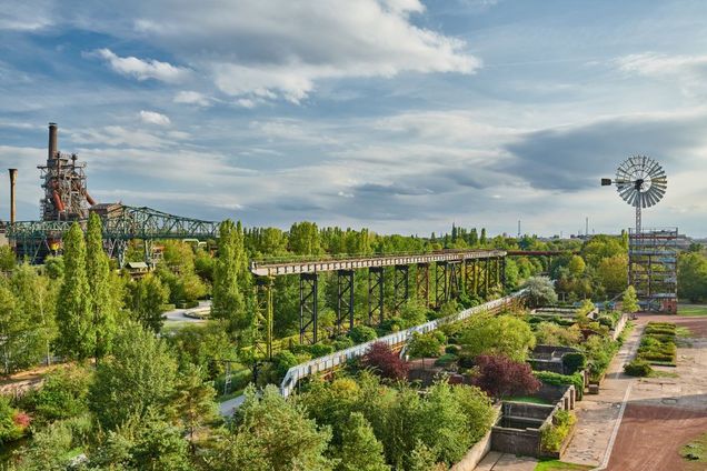 grüner Garten mit Industriekulisse im Hintergrund