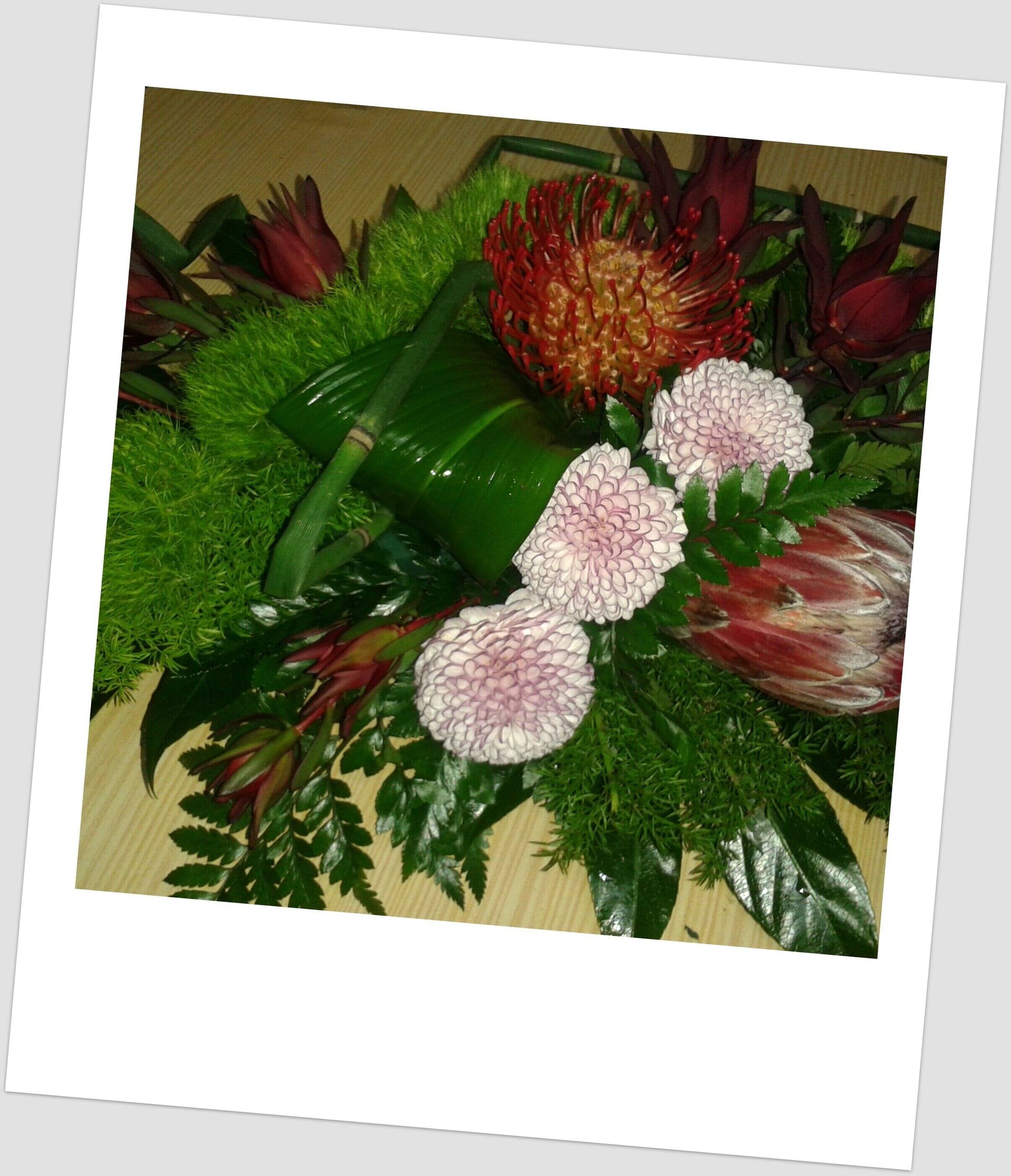 Arranjo floral colorido com flores rosa, laranja e verde.