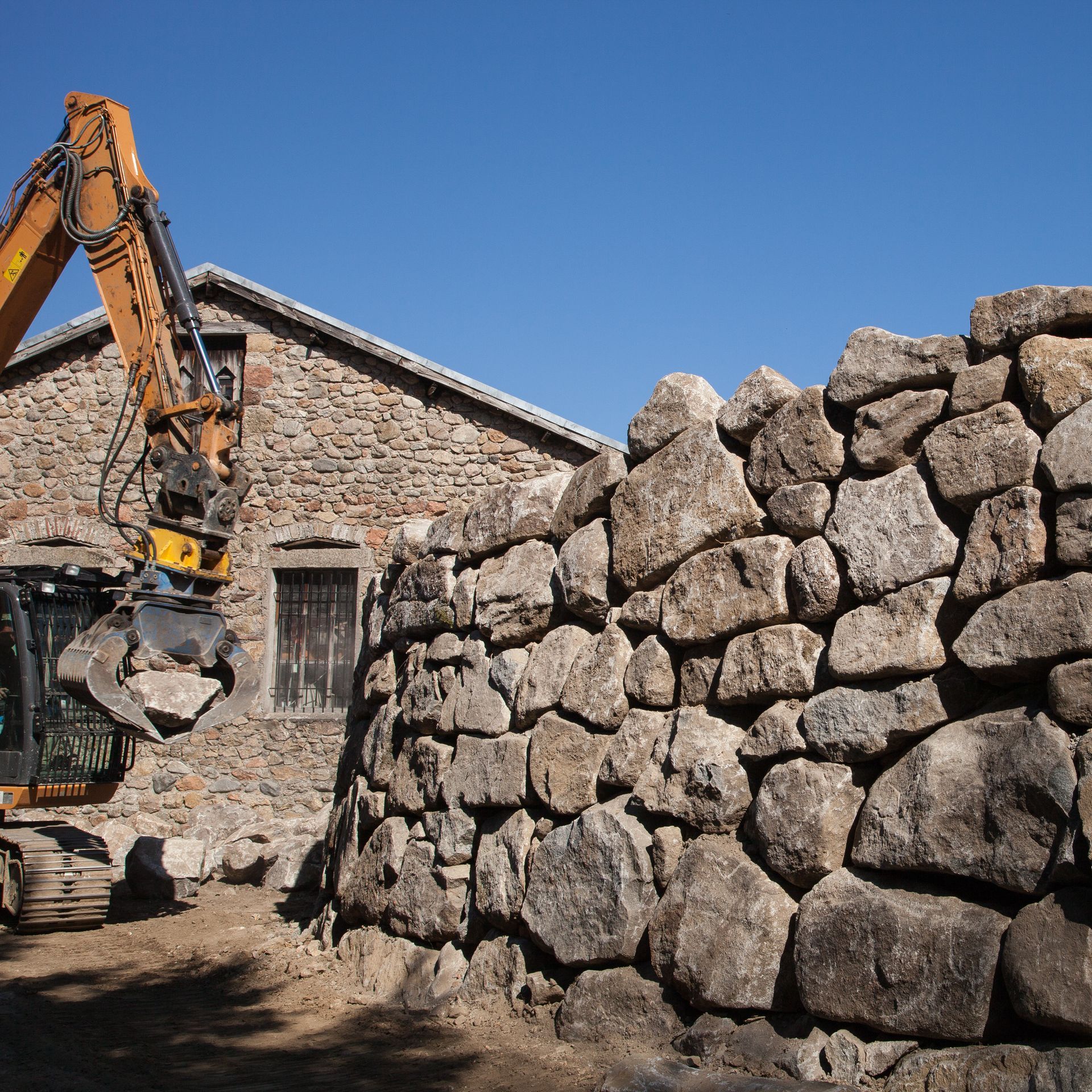 Construction en cours d'un mur en grosse pierre.