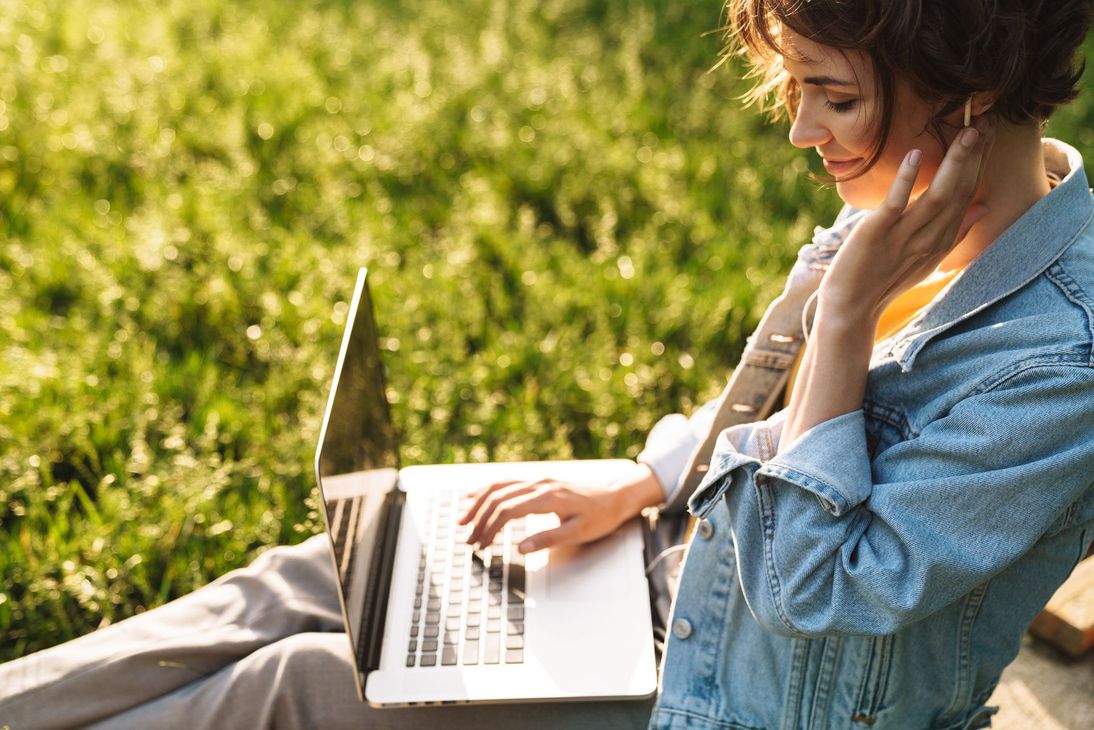 Femme sur son ordinateur assise dans son jardin