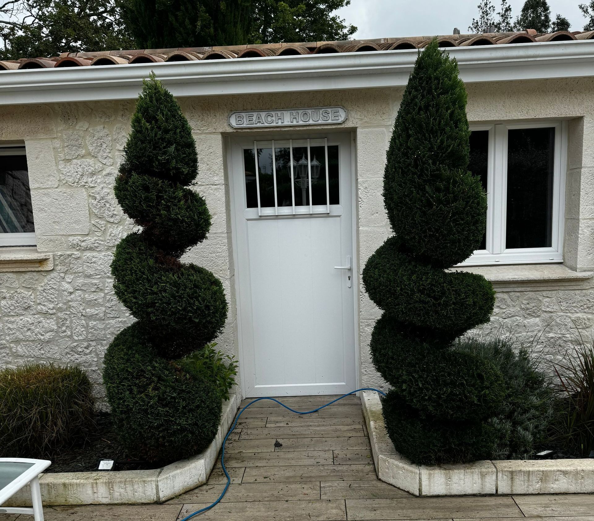 Une porte d'accès entre deux arbustes en forme de spirale.