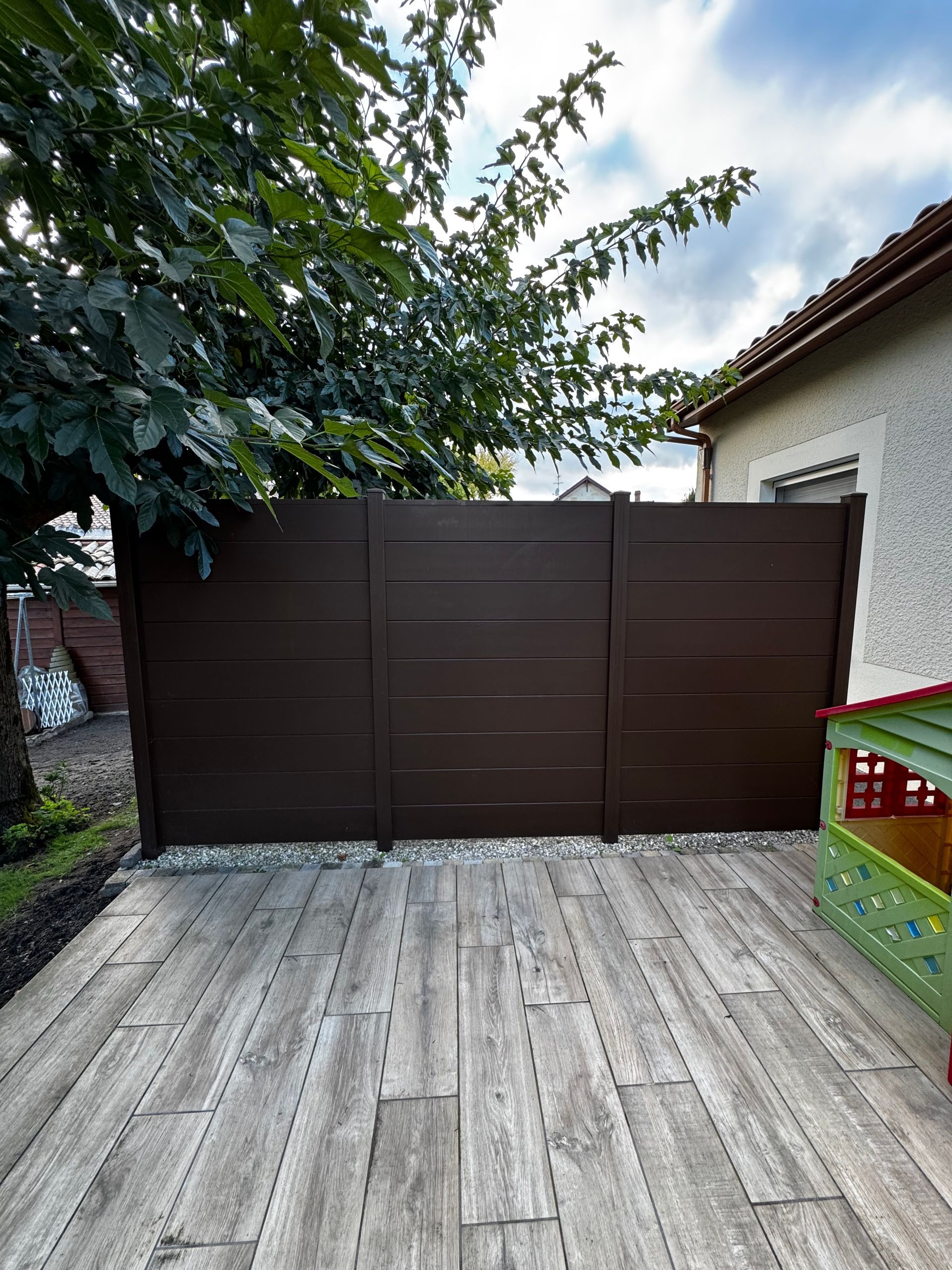 Une palissade marron au bord d'une terrasse en bois.