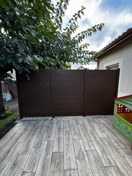 Une palissade marron au bord d'une terrasse en bois.